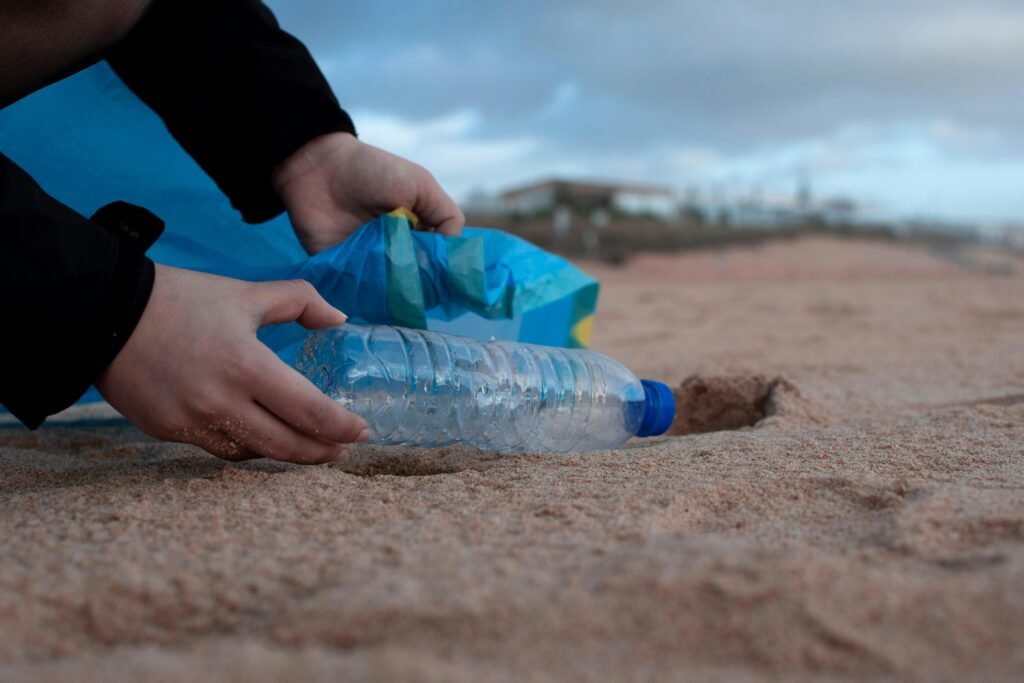 pexels photo 3480494 3480494 Hands collecting a plastic water bottle from the sandy beach, promoting environmental awareness.